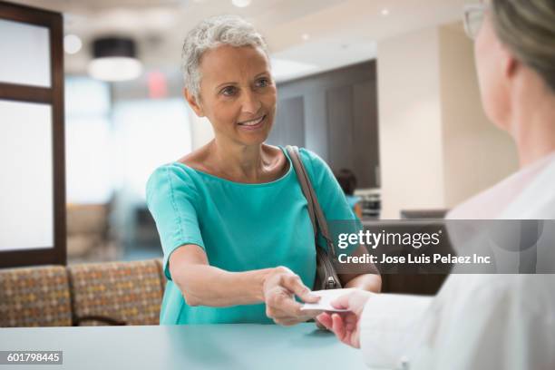 woman passing insurance card in hospital - zorgverzekering stockfoto's en -beelden