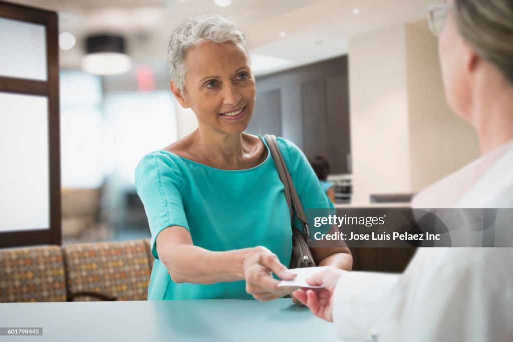 Woman passing insurance card in hospital