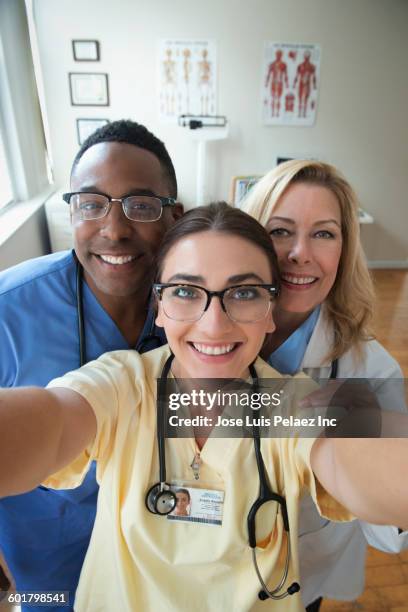 doctor and nurses taking selfie in clinic - 3 men looking up stock pictures, royalty-free photos & images