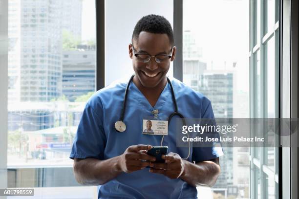 nurse using cell phone at window - doctor smartphone stock pictures, royalty-free photos & images