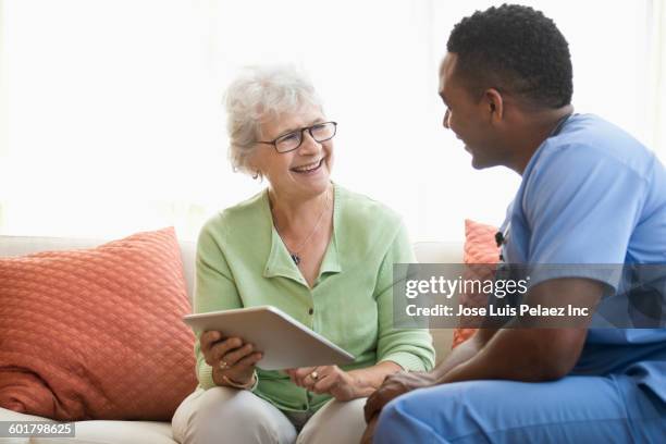 nurse and patient using digital tablet - caucasian doctor and nurse using tablet computer stock-fotos und bilder