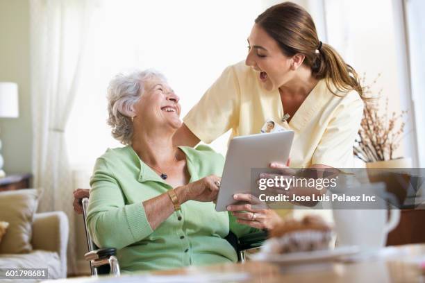 caucasian nurse and patient using digital tablet - nurse helping old woman at home stock-fotos und bilder