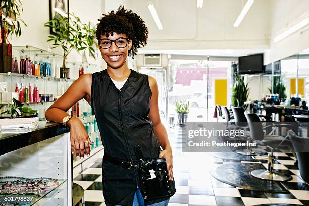 mixed race hairstylist smiling in salon - schoonheidsspecialist stockfoto's en -beelden