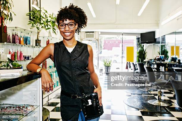 mixed race hairstylist smiling in salon - terapeuta de beleza - fotografias e filmes do acervo