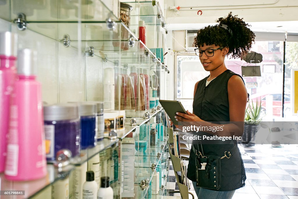 Mixed race hairstylist using digital tablet in salon