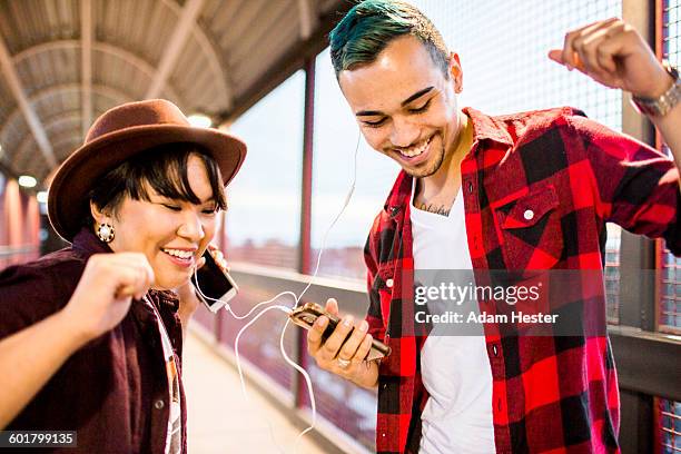 couple sharing earphones to listen to music - asian male dancer stock pictures, royalty-free photos & images