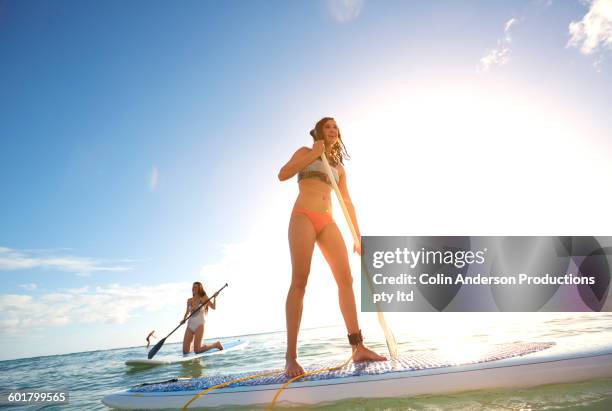 women paddle boarding in ocean - peddelen stockfoto's en -beelden