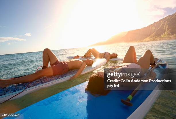 friends laying on paddle boards in ocean - hawaii fun fotografías e imágenes de stock