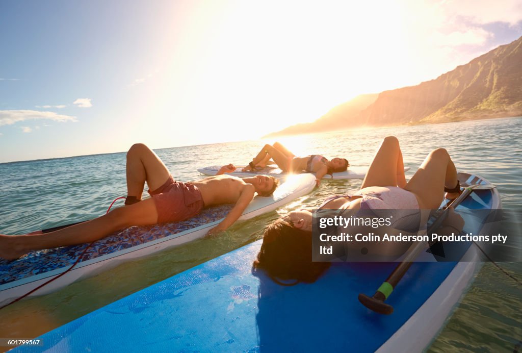 Friends laying on paddle boards in ocean