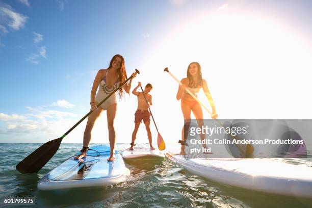 friends standing on paddle boards in ocean - paddle surf foto e immagini stock
