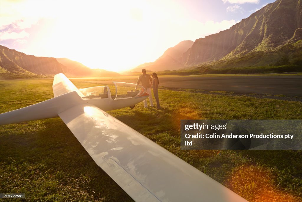 Couple admiring glider airplane on remote runway