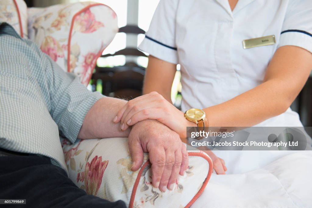 Caucasian nurse measuring pulse of patient in home