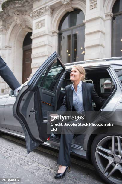 caucasian businesswoman exiting car - businesswoman blond looking left foto e immagini stock