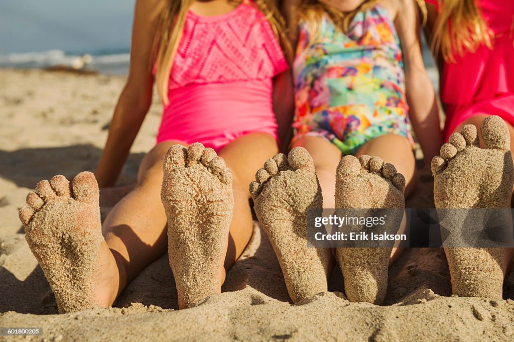 Caucasian sisters with sandy feet on beach