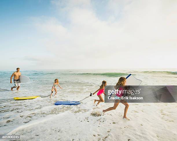 caucasian father and daughters playing in waves on beach - seascape stockfoto's en -beelden
