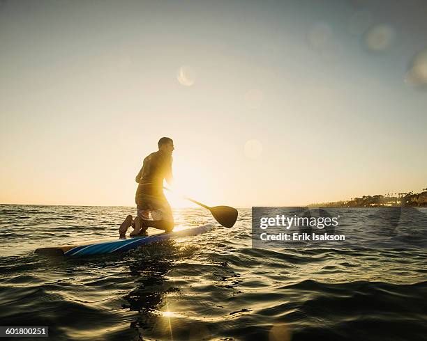 caucasian man on paddle board in ocean - paddle board men imagens e fotografias de stock