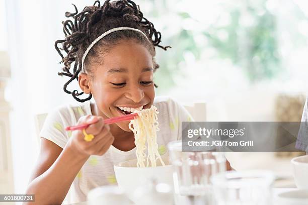 black girl eating noodles at table - asian food styling stock pictures, royalty-free photos & images