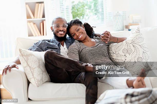 black couple smiling on sofa - lady 30s wearing glasses stock pictures, royalty-free photos & images