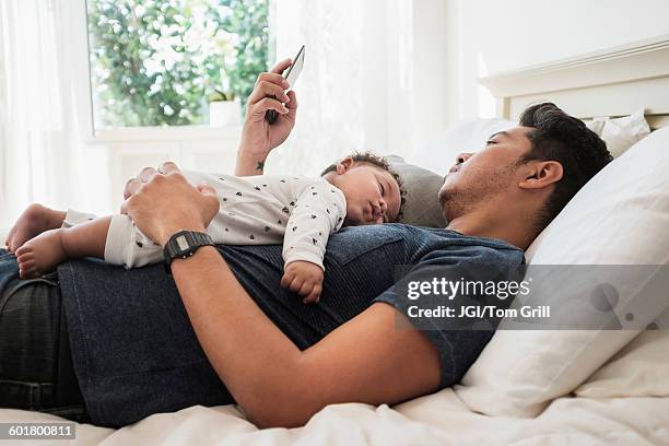 father using cell phone with sleeping baby son - baby mobile 個照片及圖片檔