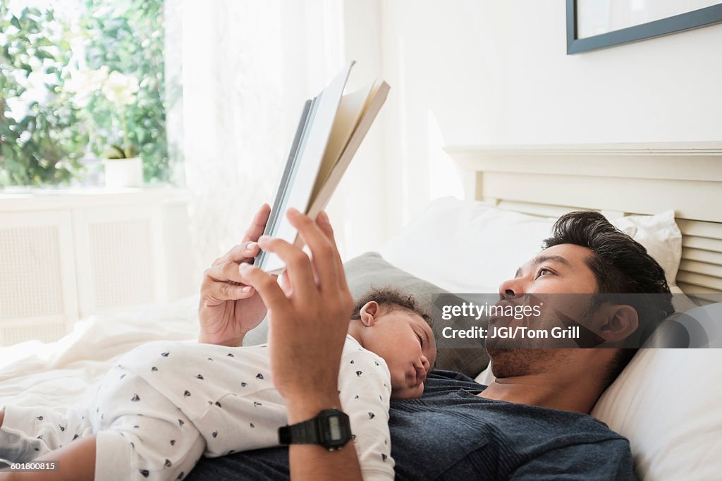 Father reading with sleeping baby son