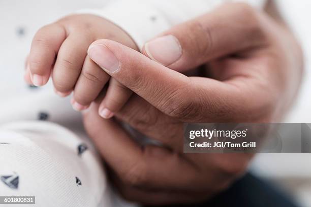 close up of father holding hand of baby son - black baby stockfoto's en -beelden