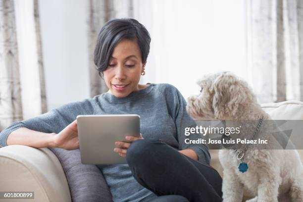 black woman using digital tablet with dog - mature reading computer stock-fotos und bilder