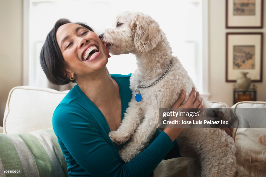 Black woman petting dog on sofa