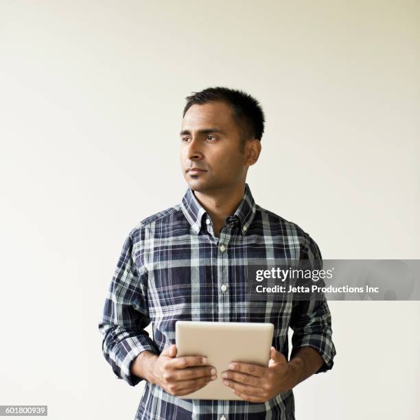 mixed race businessman holding digital tablet - portrait white background looking away stockfoto's en -beelden