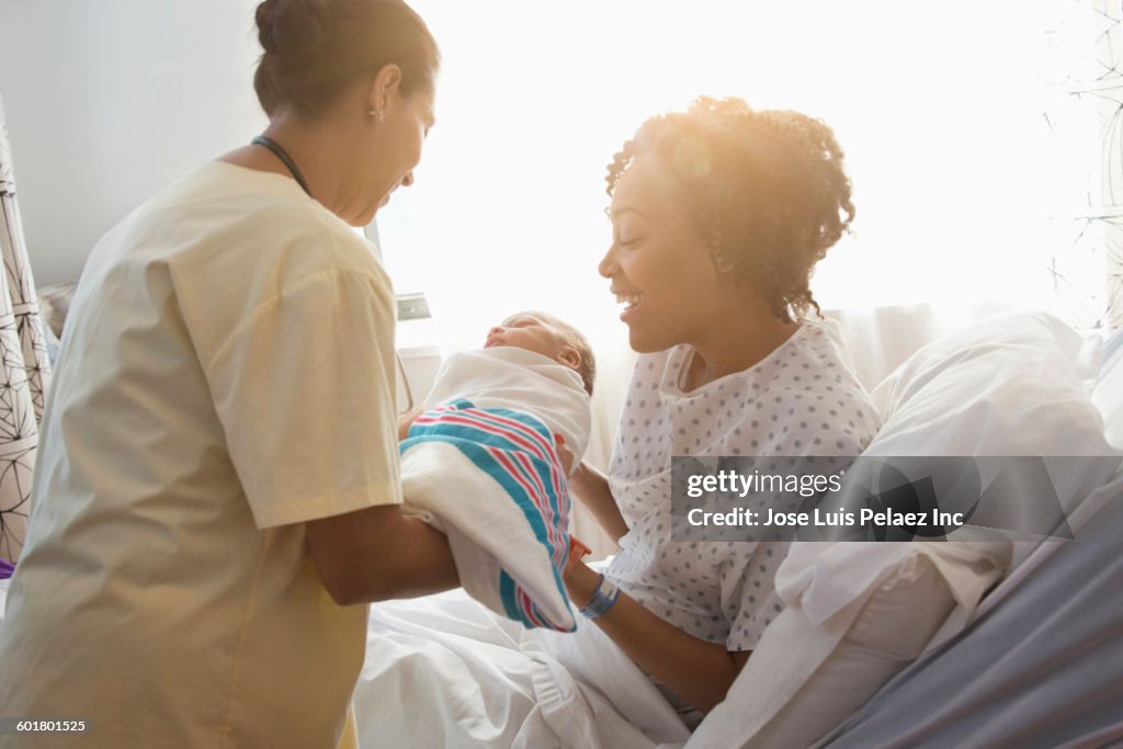 Nurse presenting newborn baby to mother