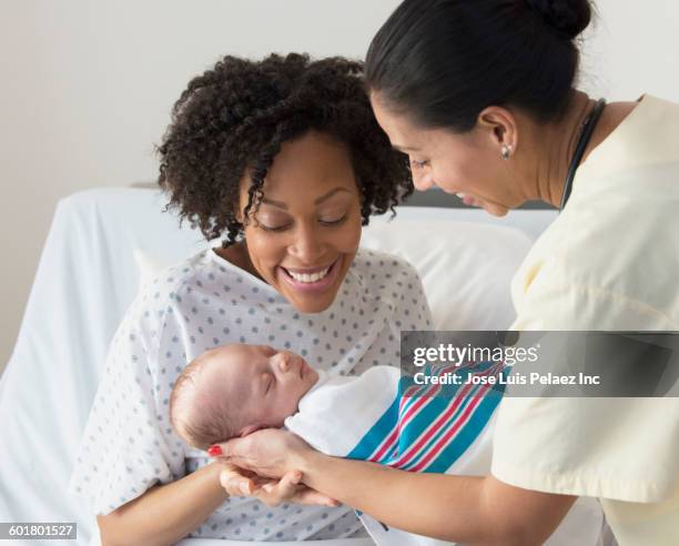 nurse presenting newborn baby to mother - three nurses stock pictures, royalty-free photos & images