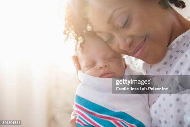 mixed race mother cradling newborn baby - moment of silence stockfoto's en -beelden