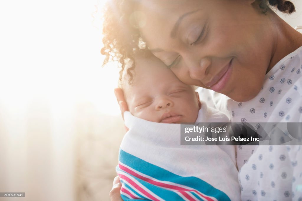 Mixed race mother cradling newborn baby