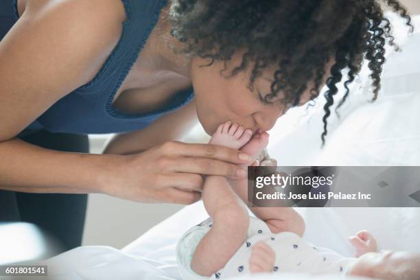 mixed race mother kissing newborn baby feet - kiss foot stock pictures, royalty-free photos & images