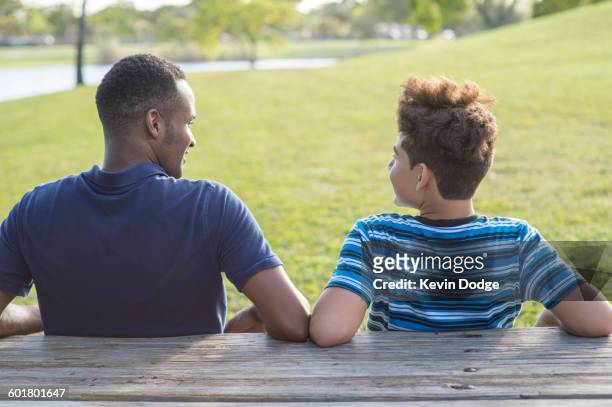 father and son sitting at table in park - dad advice stock pictures, royalty-free photos & images