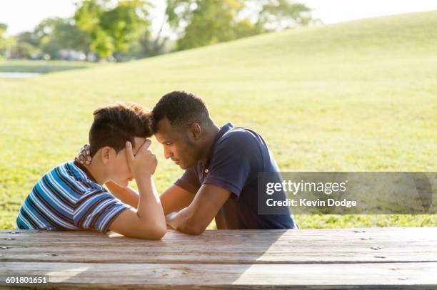 father and son talking at table in park - sad black boy stock pictures, royalty-free photos & images