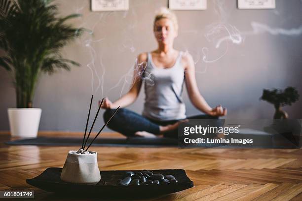 caucasian woman meditating in yoga studio - räucherwerk stock-fotos und bilder