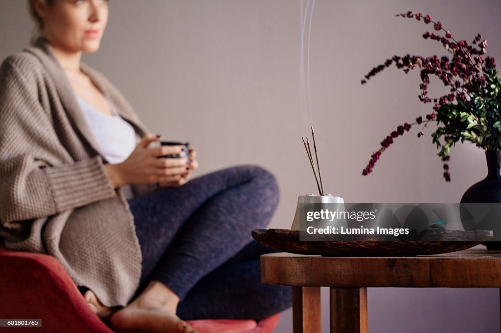 Caucasian woman burning incense in living room