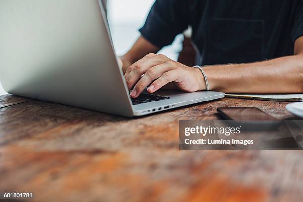 caucasian man using laptop at table - close up hand smart phone stock pictures, royalty-free photos & images