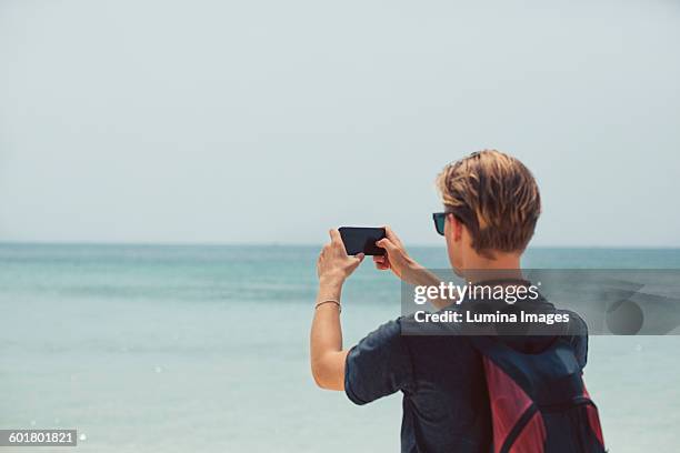 caucasian man photographing seascape - photographing foto e immagini stock