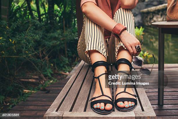 caucasian woman sitting on bench - sandales photos et images de collection