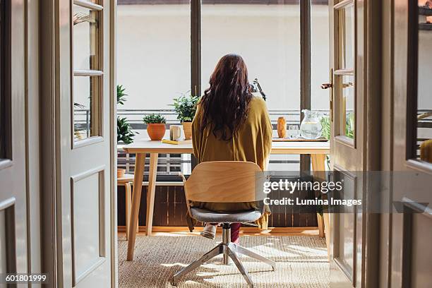 caucasian woman sitting at desk - office chair stockfoto's en -beelden