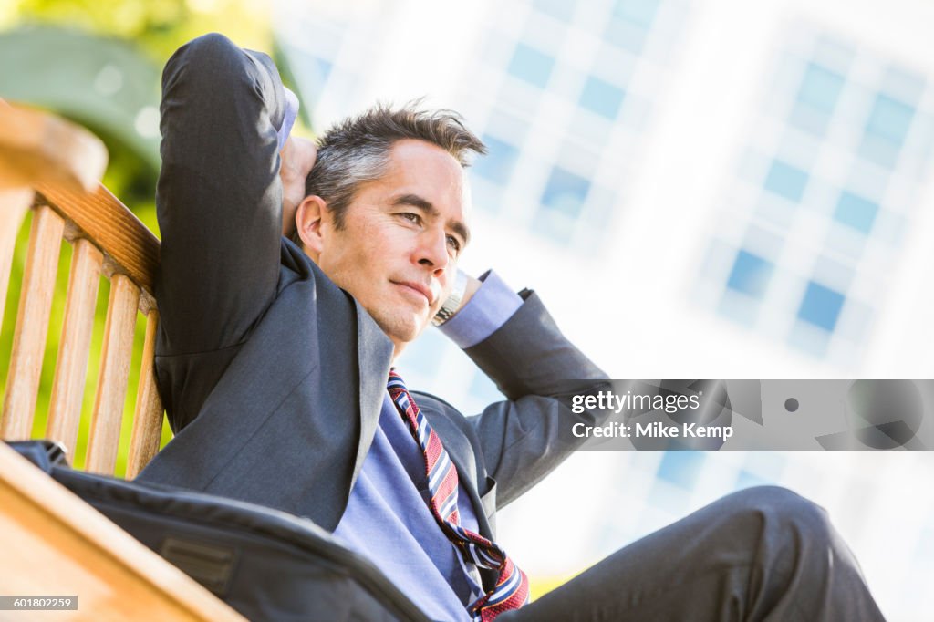 Mixed race businessman sitting outdoors