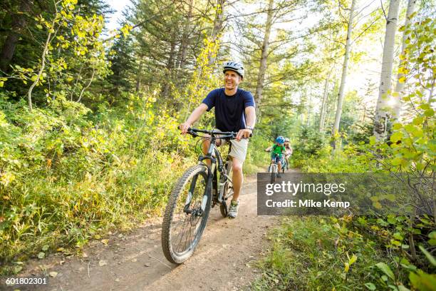 caucasian father and children riding mountain bikes - fun sommer berge stock-fotos und bilder