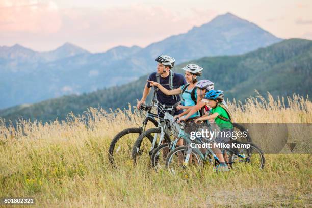 caucasian family riding mountain bikes in field - father son admiration stock pictures, royalty-free photos & images