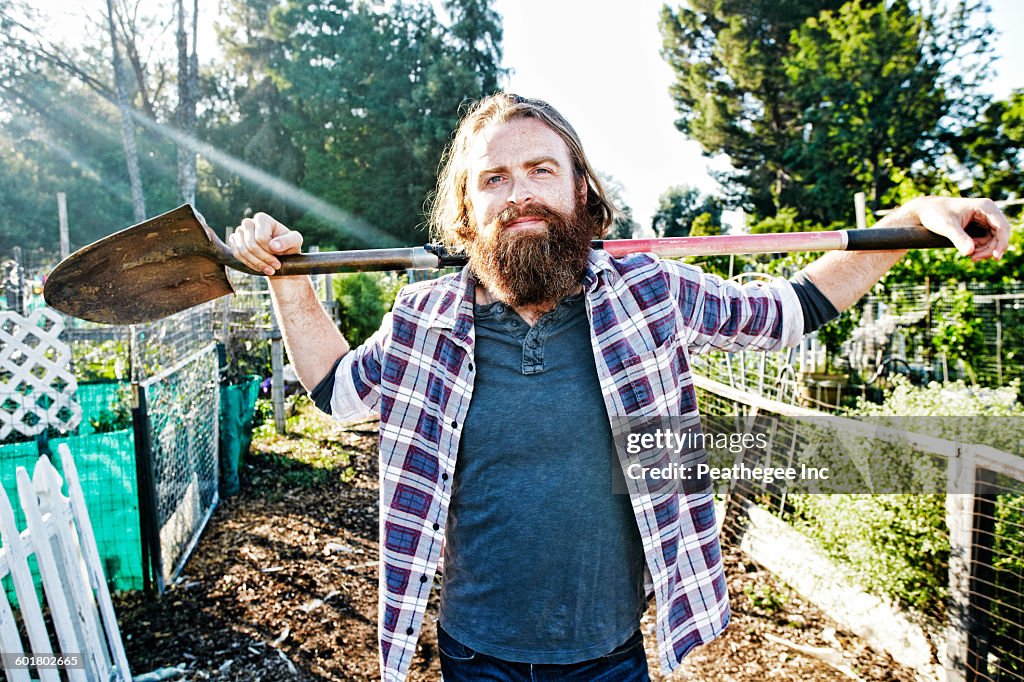 Caucasian man holding shovel in garden