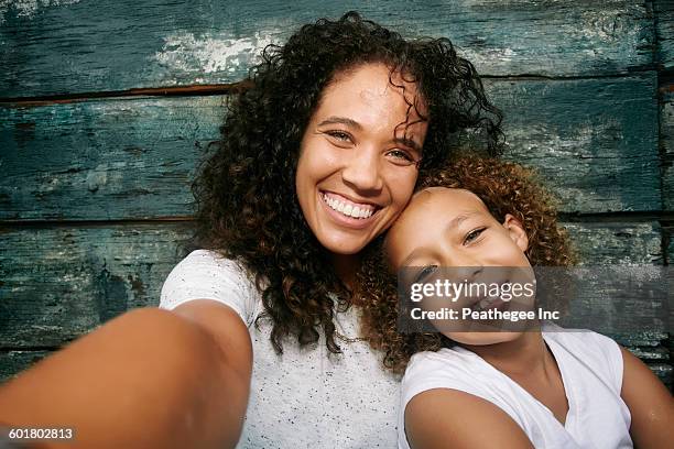 mixed race mother and daughter taking selfie - camera girls stock pictures, royalty-free photos & images