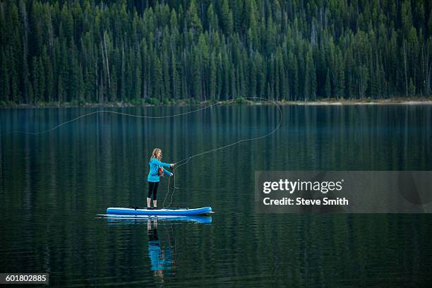 caucasian woman fishing from paddle board in river - sun valley stockfoto's en -beelden