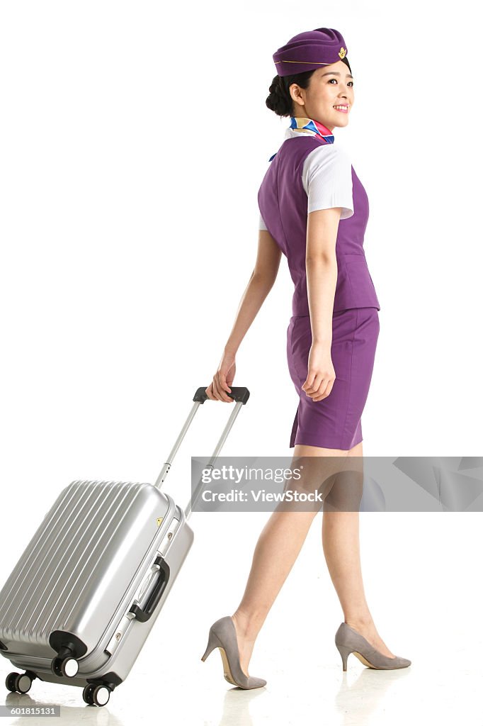 Young female cabin crew pulled a wheeled baggage