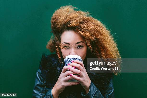 portrait of woman drinking coffee to go in front of a green wall - irish woman stock pictures, royalty-free photos & images