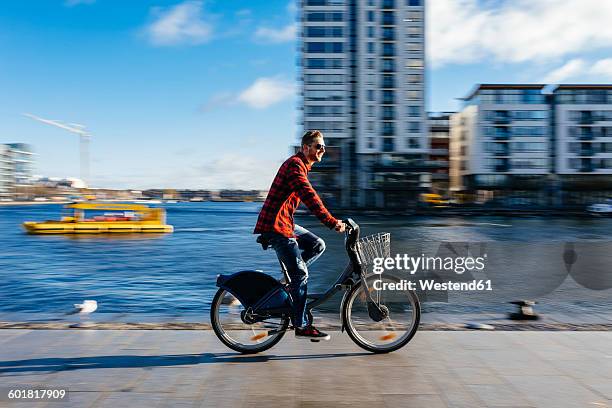 ireland, dublin, young man at city dock riding city bike - dublin fotografías e imágenes de stock